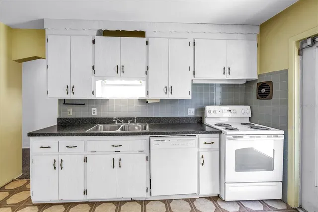 a kitchen with granite countertop white cabinets and white appliances