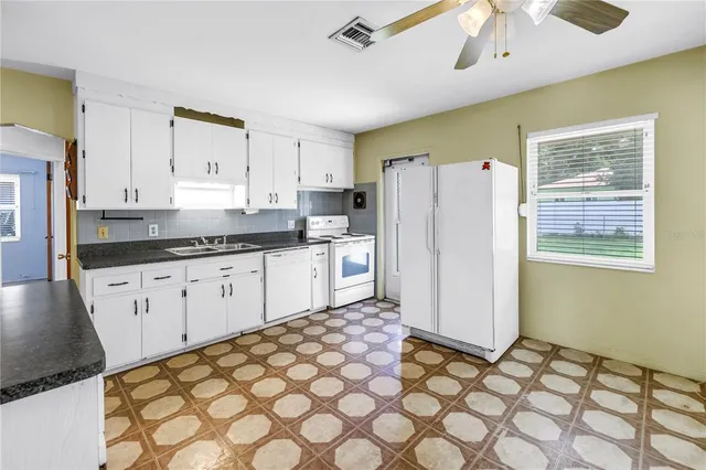 a kitchen with stainless steel appliances granite countertop a refrigerator sink and white cabinets