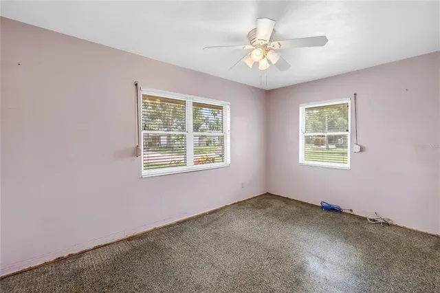 en empty room with windows and ceiling fan