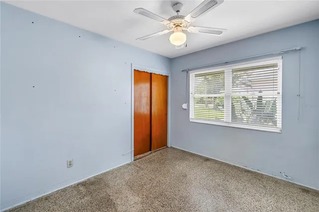 an empty room with a window and a fan
