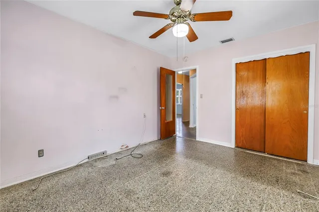 an empty room with closet and a chandelier fan
