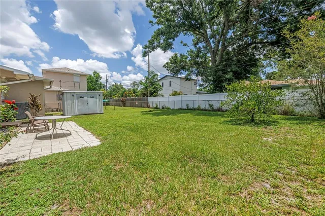 a view of a house with a big yard potted plants and large tree