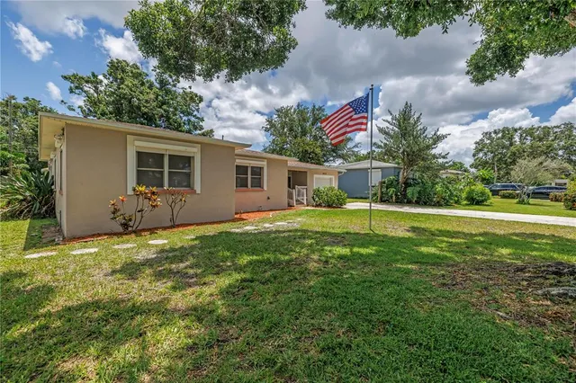 a backyard of a house with table and chairs plants and large tree