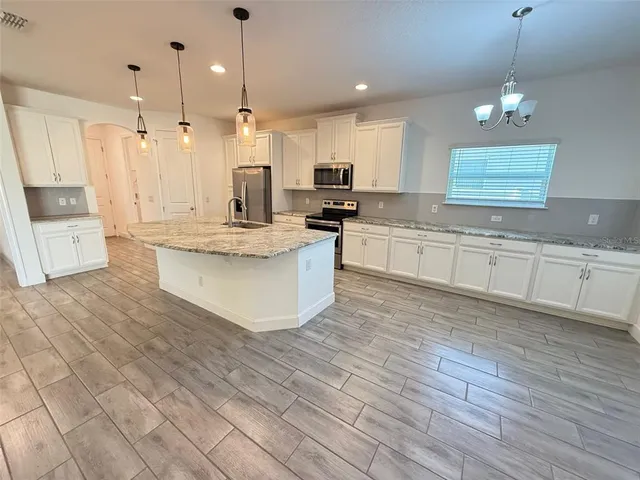 a large kitchen with kitchen island a stove a sink a center island and wooden floor