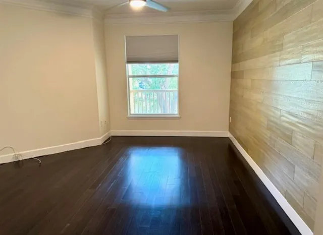 an empty room with wooden floor and ceiling fan