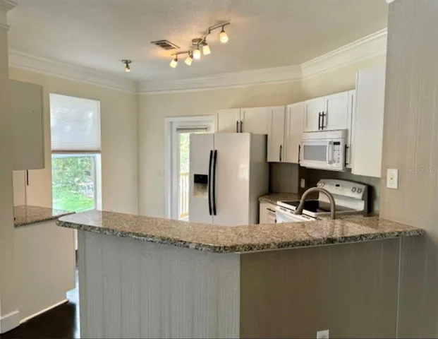a kitchen with granite countertop a stove a sink and a refrigerator