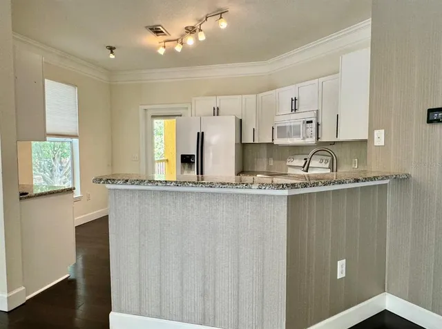 a kitchen with granite countertop white cabinets and refrigerator