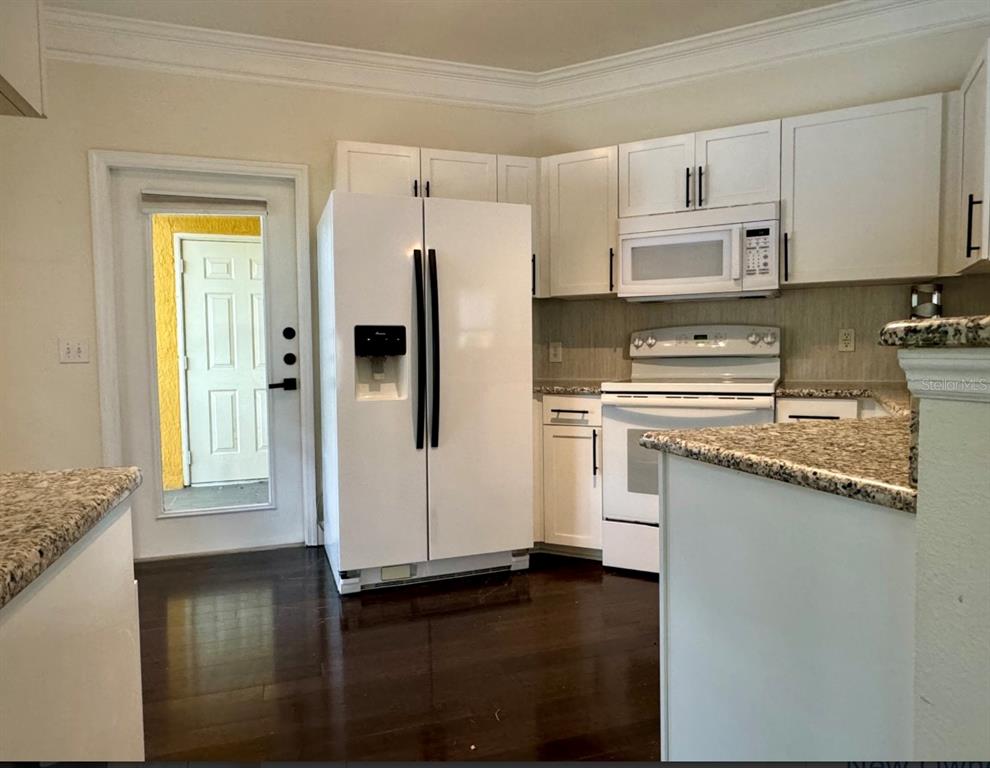 8843 Villa View Circle, Unit 207 Orlando, FL 32821 - Photo 7 of 36 a kitchen with granite countertop white cabinets and refrigerator