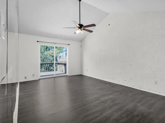 a view of an empty room with a ceiling fan and wooden floor