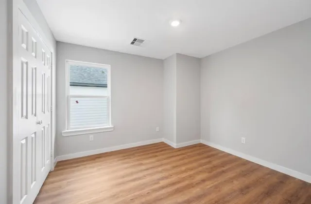 a view of empty room with wooden floor and fan