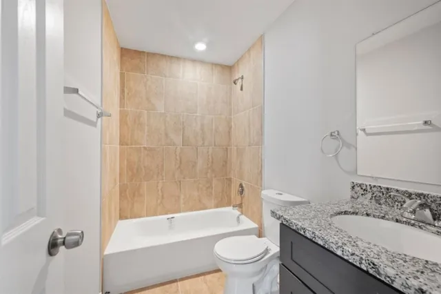 a bathroom with a granite countertop sink a toilet and shower