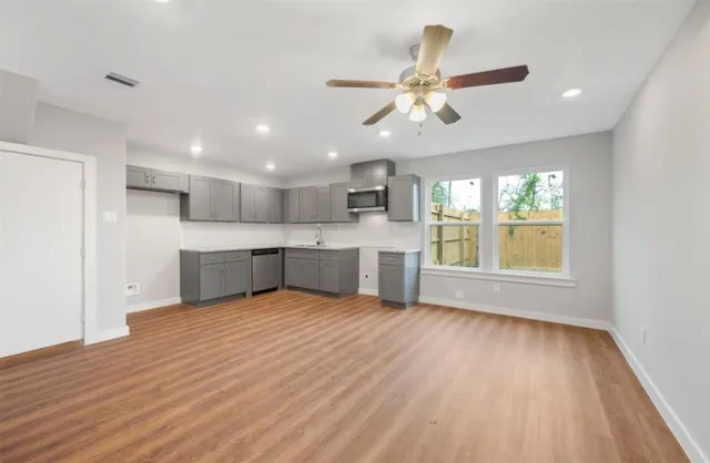 a view of an empty room with window wooden floor and kitchen view