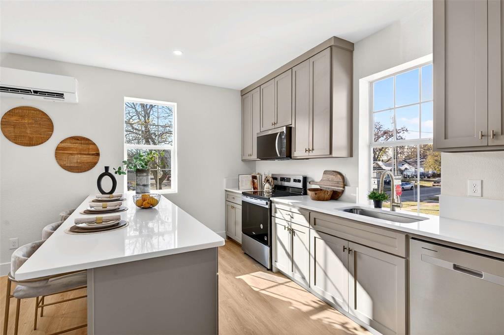 a kitchen with stainless steel appliances granite countertop a sink a stove top oven a chimney and cabinets