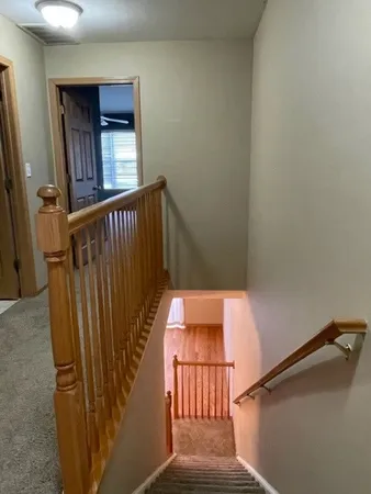 a view of staircase with railing and a chandelier