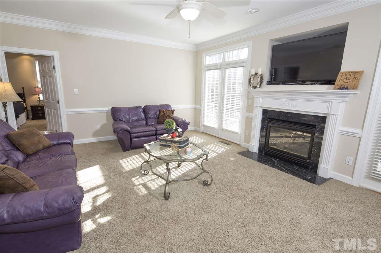 6407 Wimberly Road Willow Spring, NC 27592 - Photo 13 of 25 a living room with furniture a fireplace and a flat screen tv