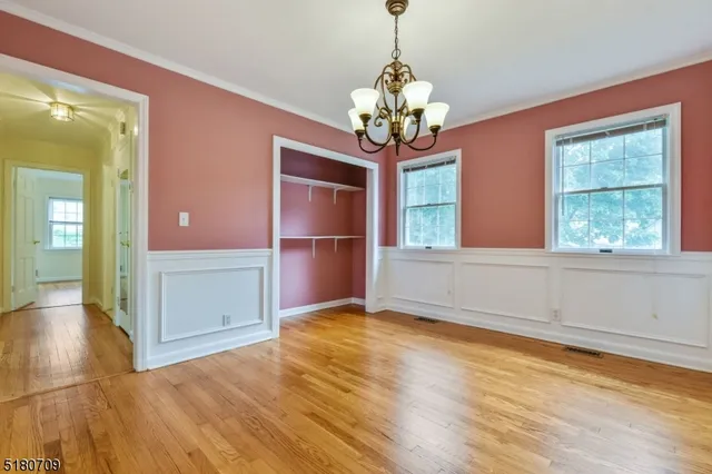 a view of a room with wooden floor chandelier and windows