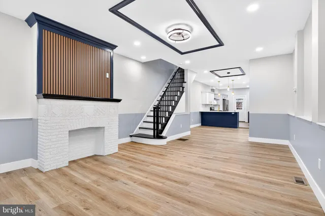 a view of an empty room with wooden floor and stairs