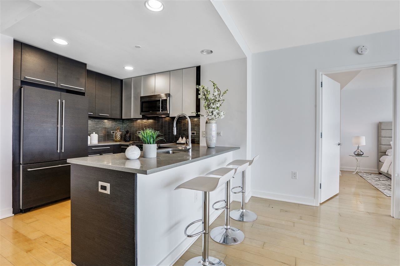 2 2nd Street, Unit 2803 Jersey City, NJ 07302 - Photo 8 of 28 a kitchen with kitchen island a counter top space cabinets and stainless steel appliances