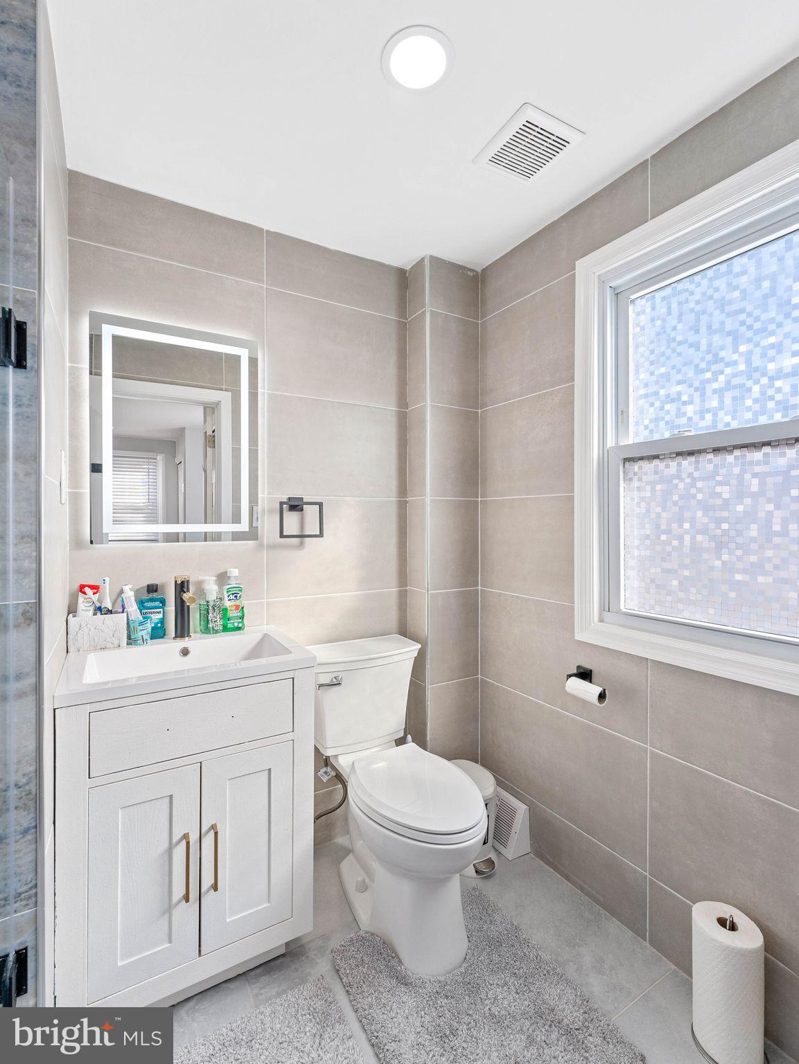 1152 Morefield Road Philadelphia, PA 19115 - Photo 10 of 29 a bathroom with a toilet a sink a mirror a window and vanity