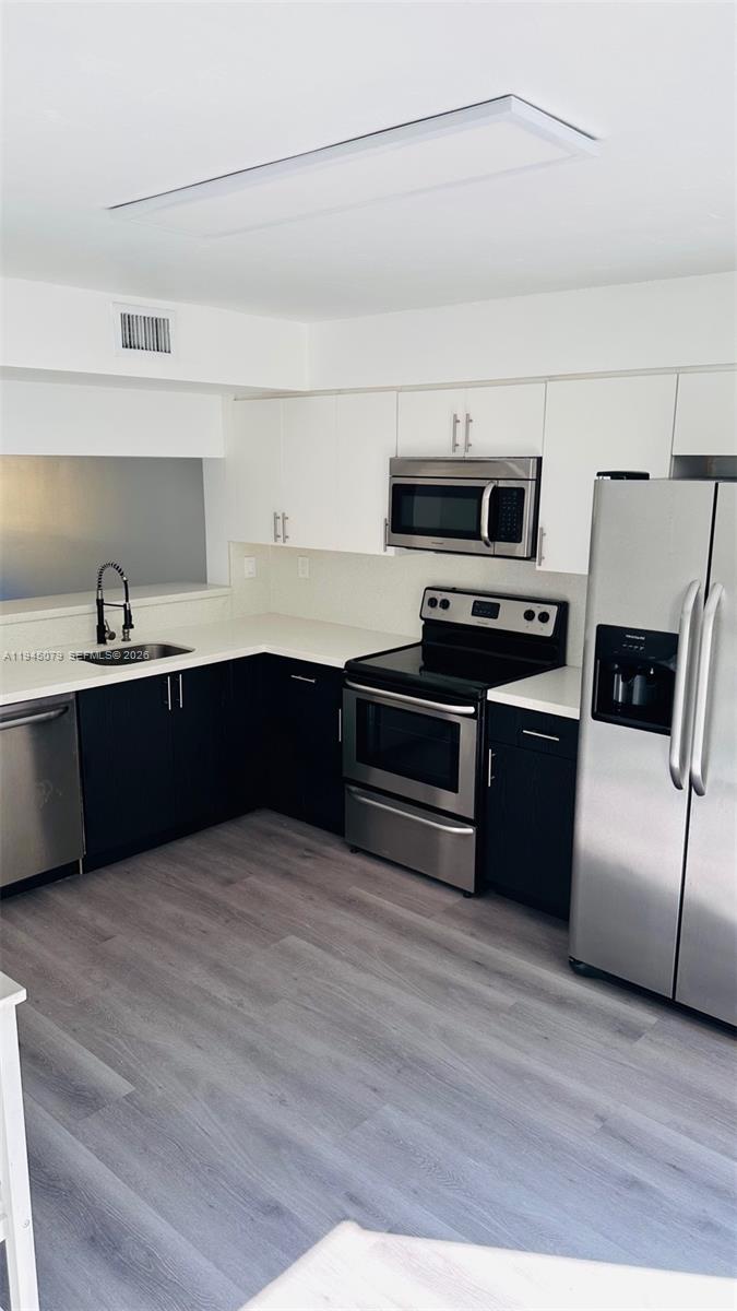 8240 Southwest 149th Court, Unit 7205 Miami, FL 33193 - Photo 7 of 14 a kitchen with wooden cabinets and stainless steel appliances