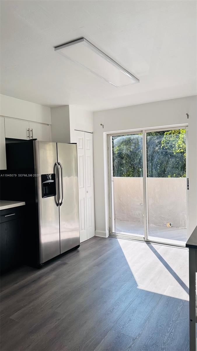 8240 Southwest 149th Court, Unit 7205 Miami, FL 33193 - Photo 8 of 14 a view of a refrigerator in kitchen and an empty room with wooden floor