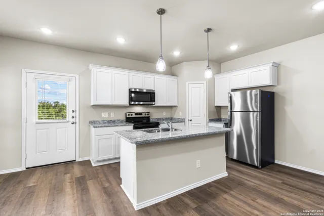 a kitchen with stainless steel appliances granite countertop a refrigerator a sink dishwasher a stove and white cabinets with wooden floor