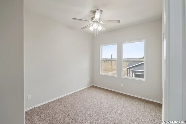 an empty room with windows and chandelier fan