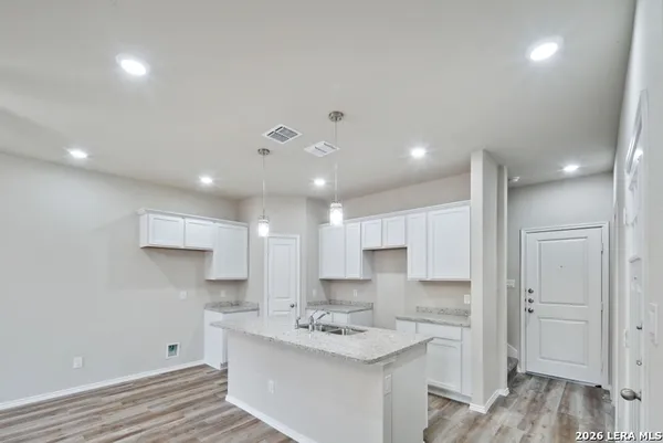 a kitchen with a sink stainless steel appliances white cabinets and wooden floor