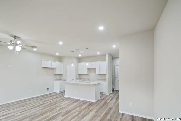 a open kitchen with kitchen island a sink dishwasher a refrigerator and white cabinets with wooden floor