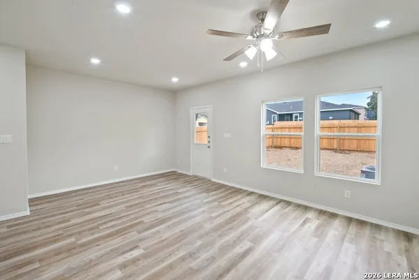 an empty room with windows and ceiling fan