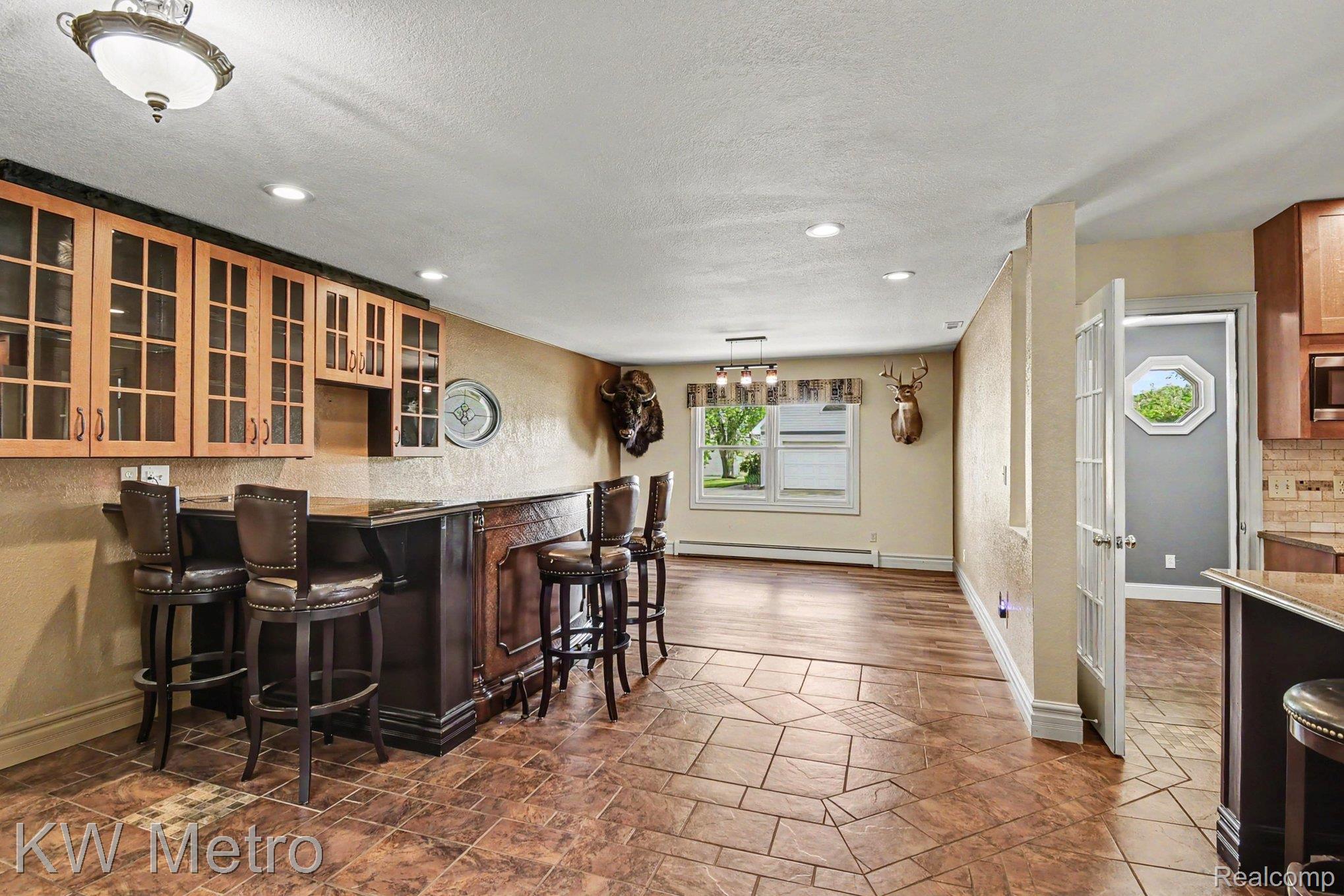 2682 East Haskell Lake Road Harrison, MI 48625 - Photo 14 of 61 Expansive entertainment area featuring a built-in wet bar with wood-finish cabinetry, a patterned tile floor, recessed lighting, and a window providing natural light