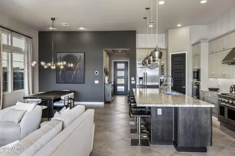 a living room with couches kitchen view and a large window