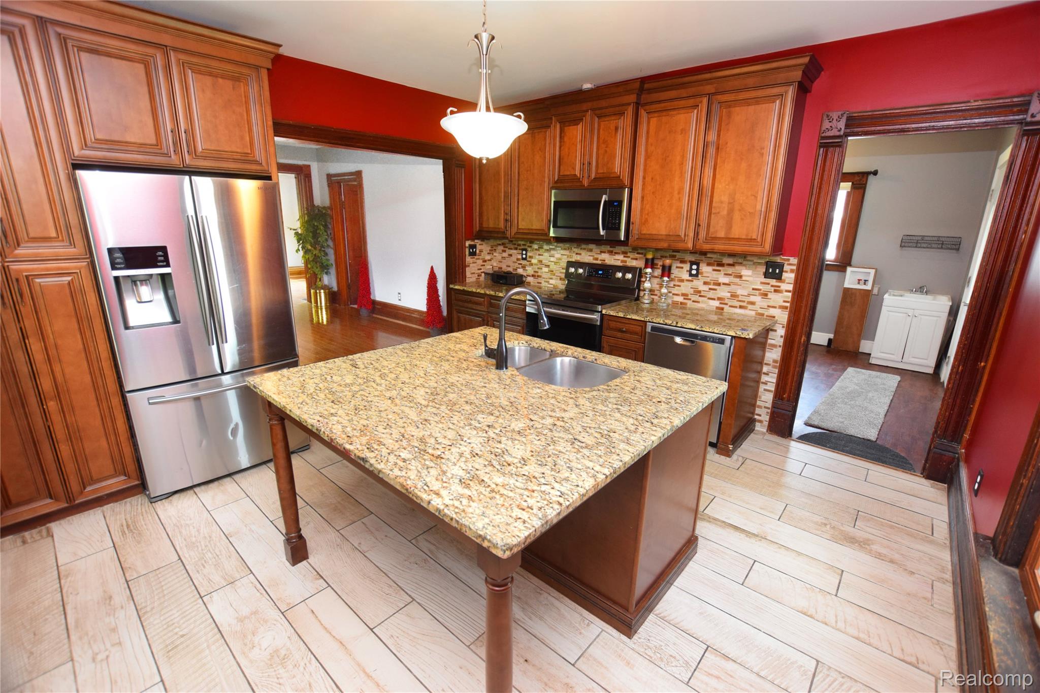 404 North Adelaide Street Fenton, MI 48430 - Photo 3 of 23 Kitchen featuring a granite-topped island with an undermount sink, stainless steel appliances, and wood-finish flooring