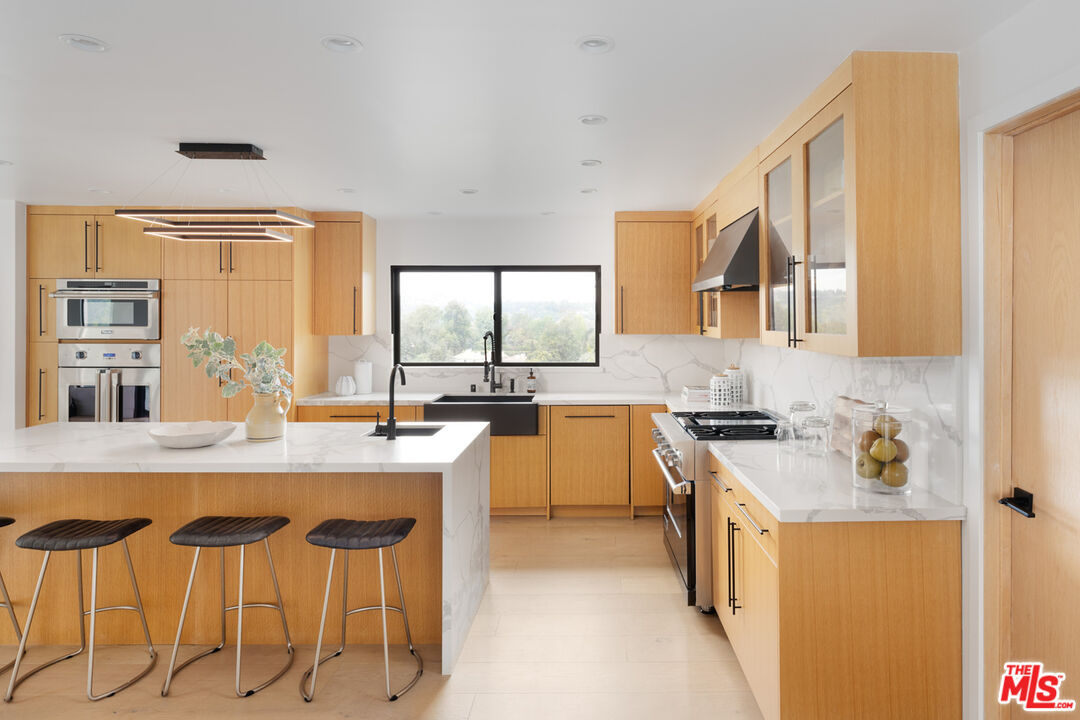 9645 Highridge Drive Beverly Hills, CA 90210 - Photo 3 of 29 a kitchen with a table chairs sink and cabinets