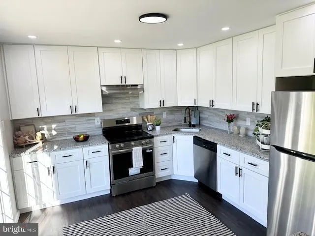 a kitchen with stainless steel appliances granite countertop a stove a sink and a refrigerator