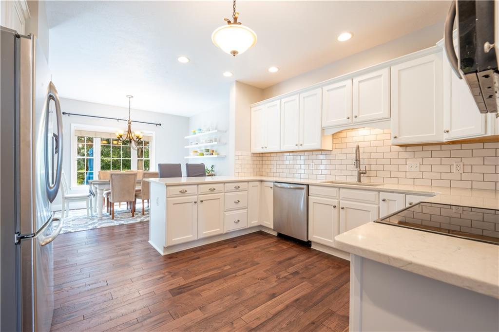 121 Stoney Springs Road Greensburg, PA 15601 - Photo 17 of 45 a kitchen with a sink a stove a refrigerator and white cabinets with wooden floor