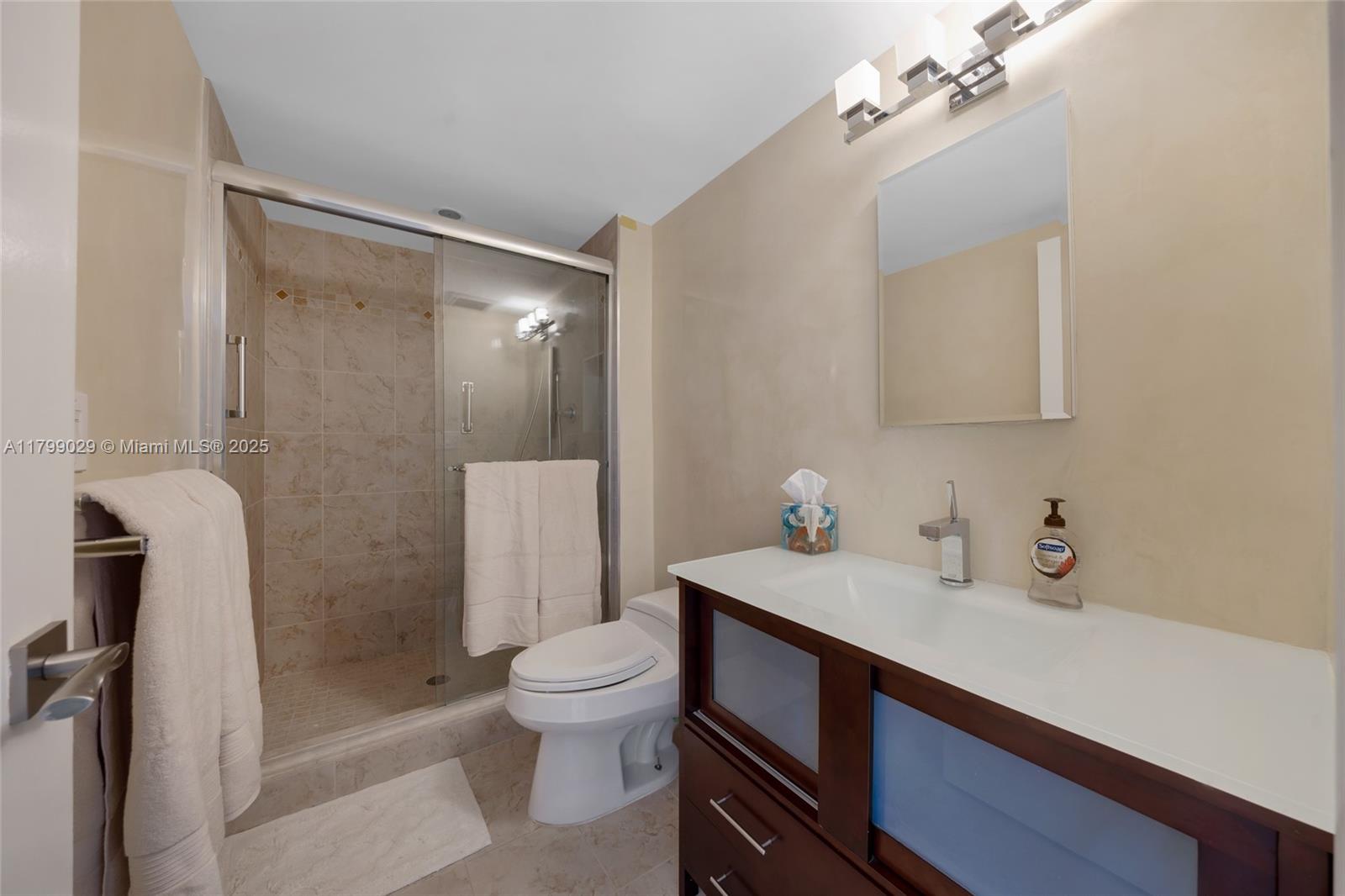 9801 Collins Avenue, Unit 5S Bal Harbour, FL 33154 - Photo 17 of 32 a bathroom with a sink a toilet a mirror and shower