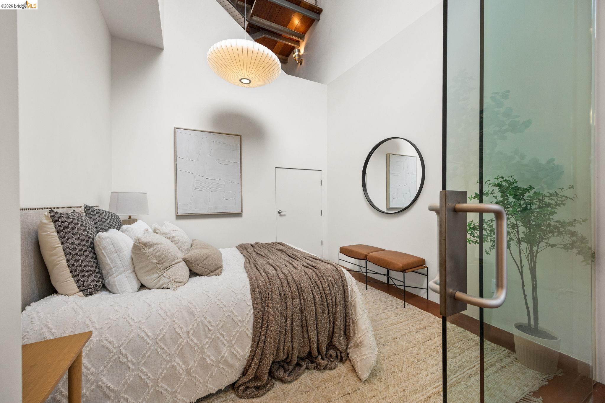 2709 Tenth Street, Unit D Berkeley, CA 94710 - Photo 9 of 29 High vaulted ceiling with exposed wood beams, modern pendant light fixture, glass wall with exterior foliage, and a contemporary round mirror
