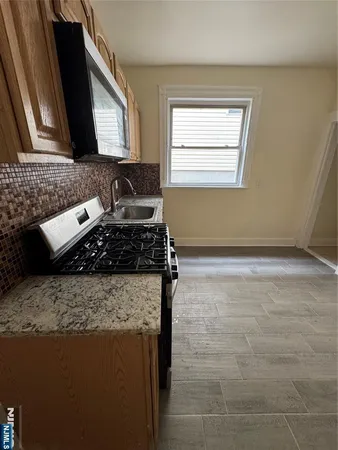 a kitchen with granite countertop a stove a sink and a microwave