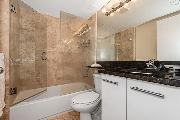 a bathroom with a granite countertop sink toilet and shower