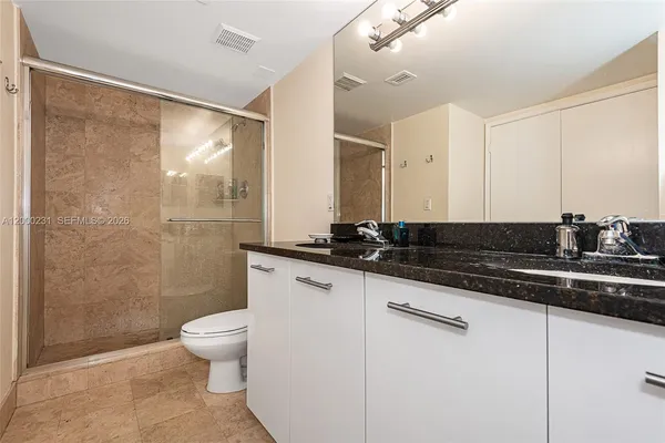 a bathroom with a granite countertop sink a toilet a mirror and shower