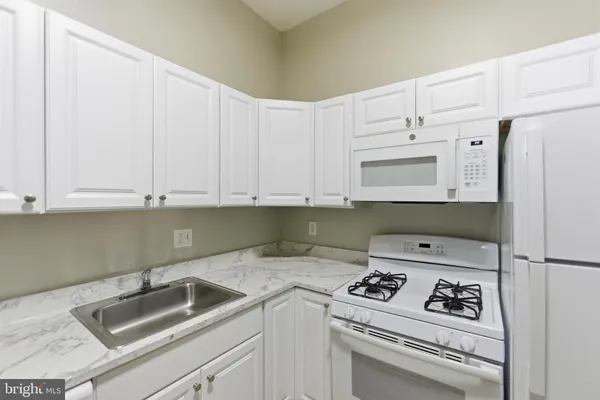 a kitchen with a refrigerator a stove and wooden floor
