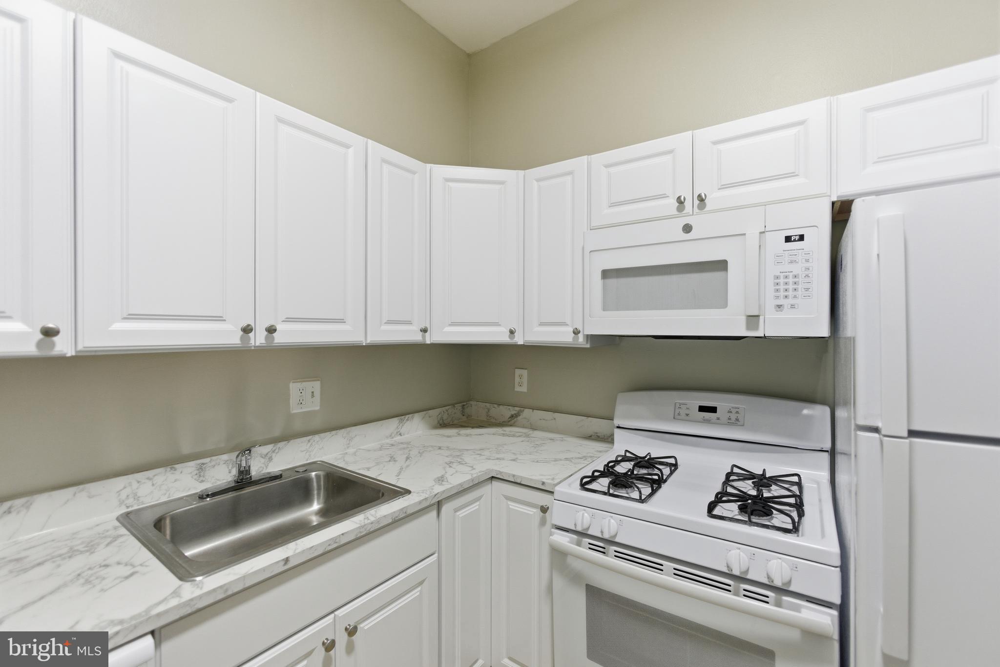 18806 Walkers Choice Road, Unit 2 Montgomery Village, MD 20886 - Photo 10 of 18 a kitchen with white cabinets sink and white appliances