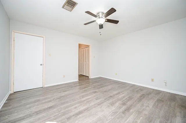 an empty room with wooden floor and ceiling fan