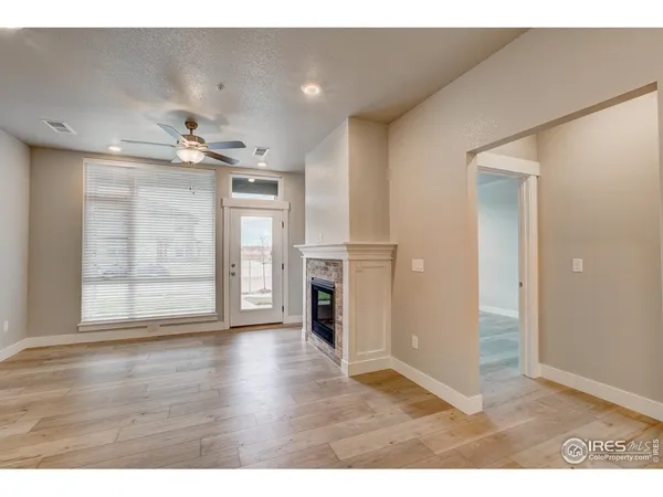 a view of an empty room with wooden floor and a fireplace
