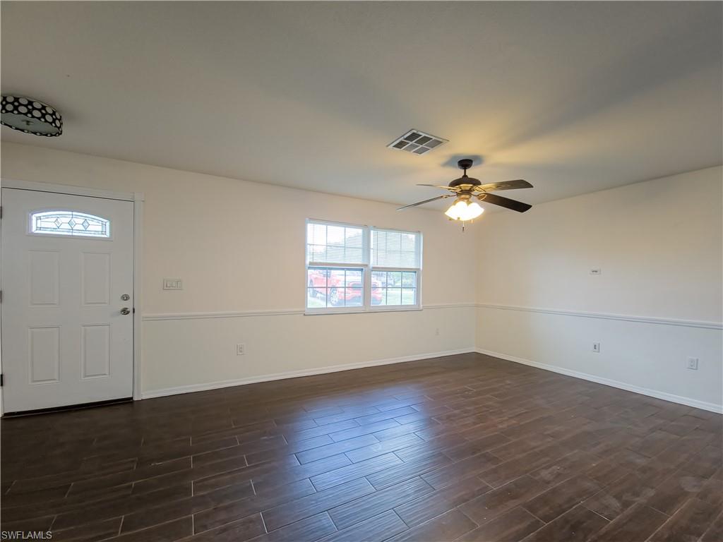 7425 Galloway Road Weeki Wachee, FL 34613 - Photo 2 of 23 an empty room with wooden floor chandelier fan and windows