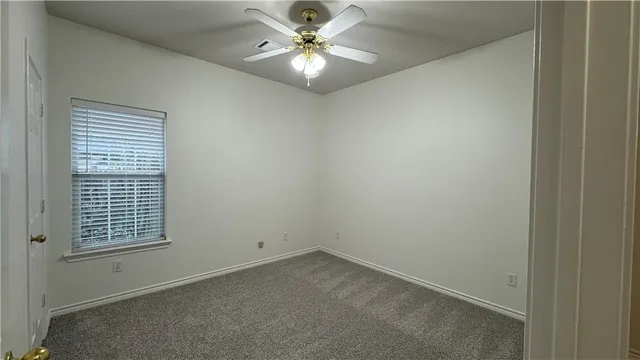 an empty room with windows and fan