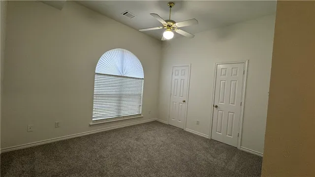 an empty room with windows and fan