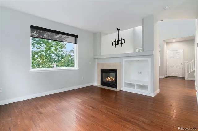 an empty room with wooden floor a fireplace and windows