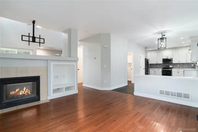 a view of kitchen and empty room with wooden floor